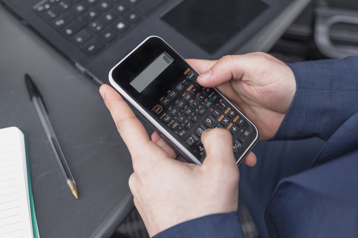 Pessoa segurando com as duas mãos uma calculadora.